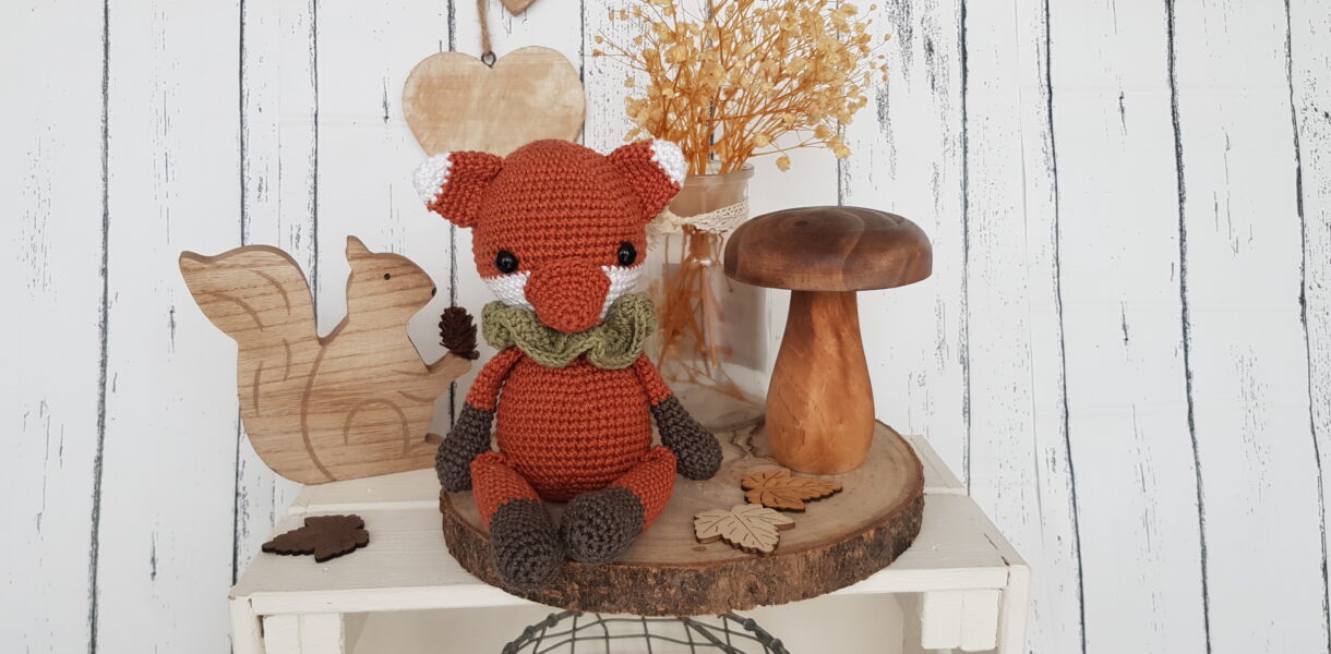 tommy the fox sitting next to a wooden mushroom and a wooden squirrel