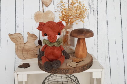 tommy the fox sitting next to a wooden mushroom and a wooden squirrel