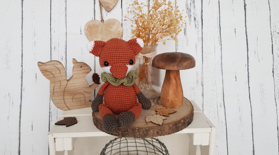 tommy the fox sitting next to a wooden mushroom and a wooden squirrel