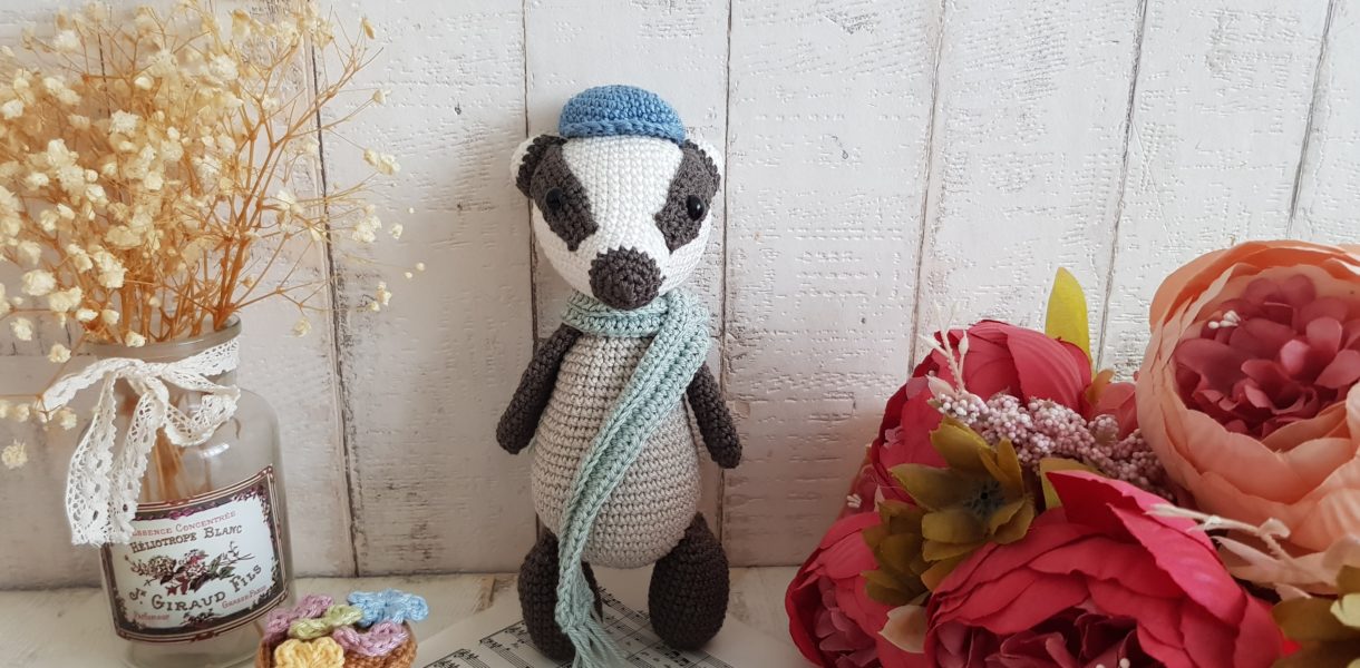 crochet badger standing with a scarf around his neck