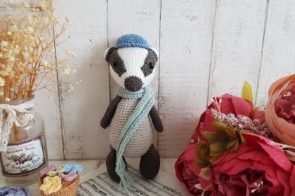 crochet badger standing with a scarf around his neck