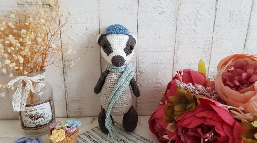 crochet badger standing with a scarf around his neck