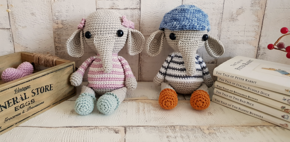 crochet elephants sitting next to some books