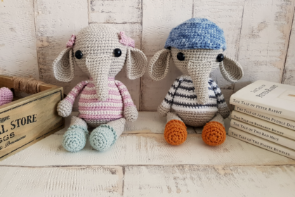 crochet elephants sitting next to some books