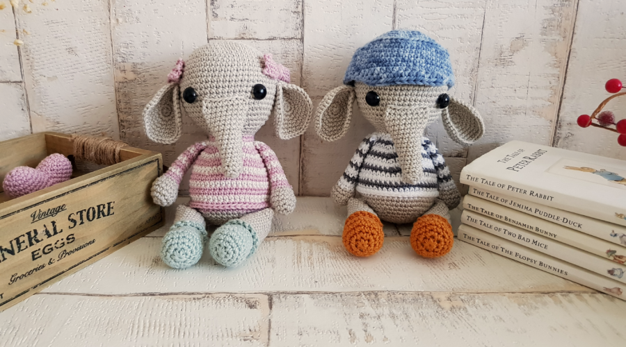 crochet elephants sitting next to some books