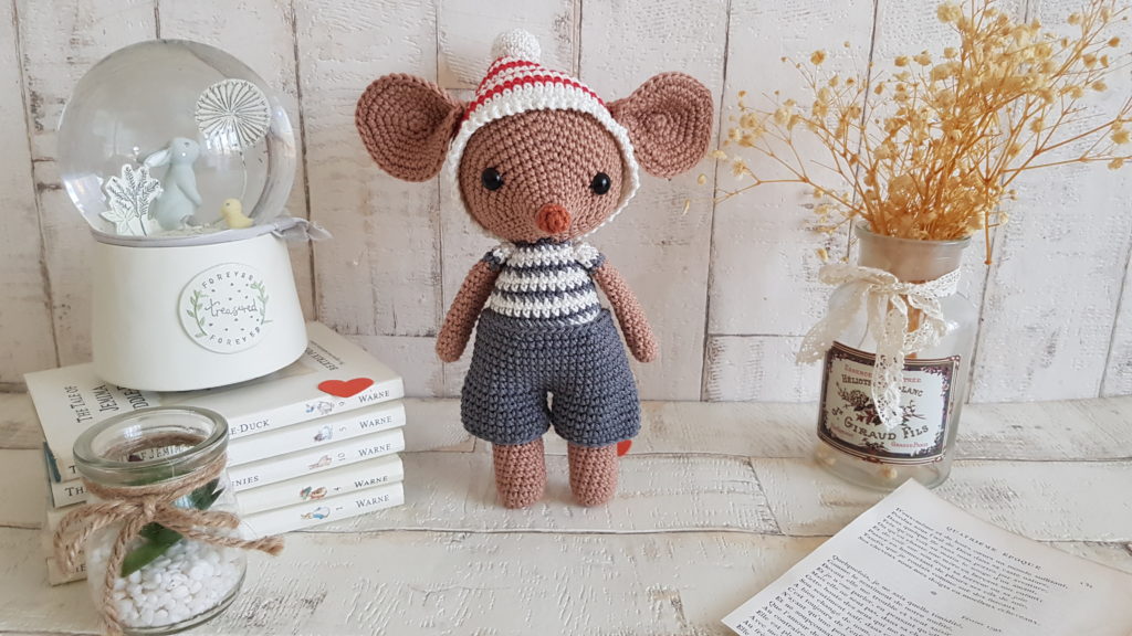 crochet mouse standing next to a baby music box