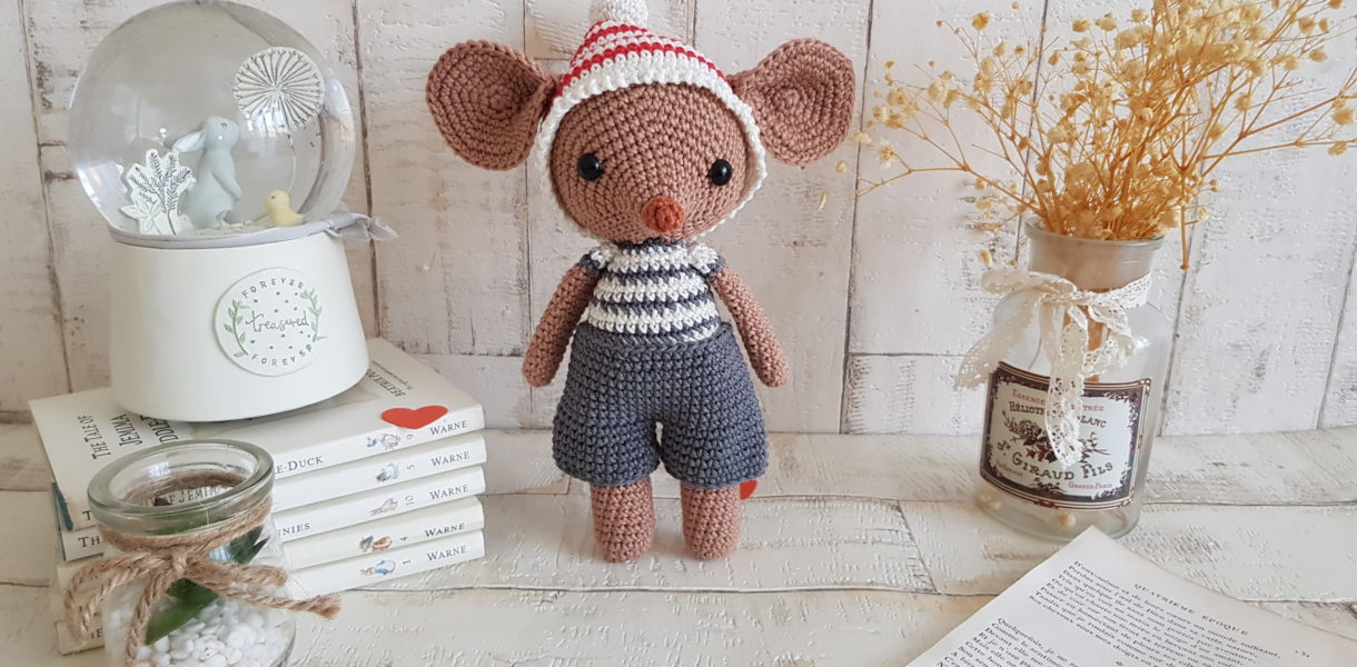 crochet mouse standing next to a baby music box