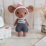 crochet mouse standing next to a baby music box