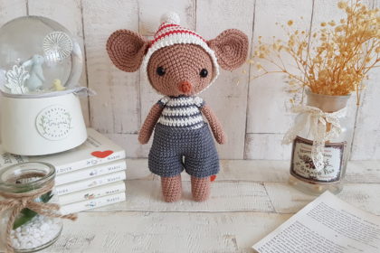 crochet mouse standing next to a baby music box