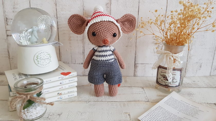 crochet mouse standing next to a baby music box