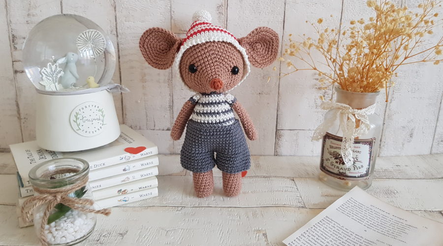 crochet mouse standing next to a baby music box