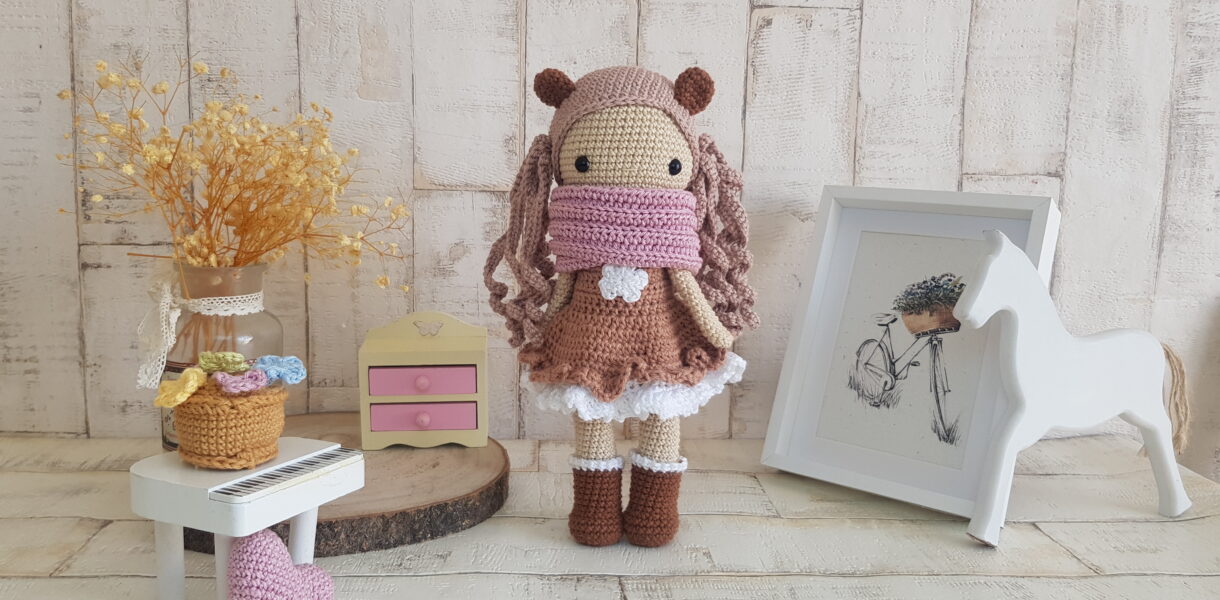 crochet doll standing next to a piano, a rocking horse and a nice painting