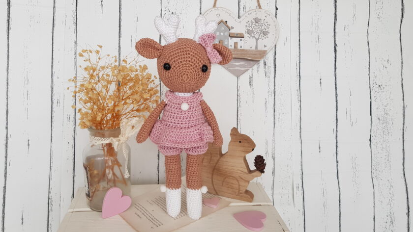 crochet deer standing next to a wooden squirrel