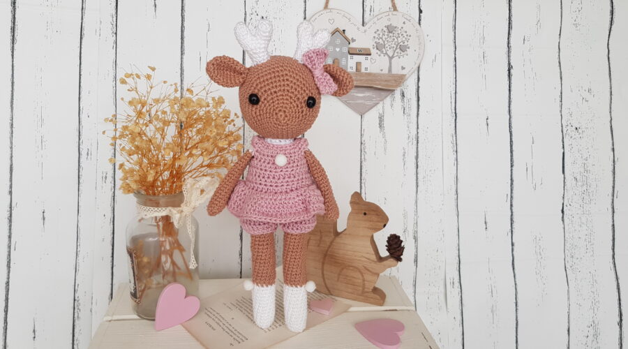 crochet deer standing next to a wooden squirrel